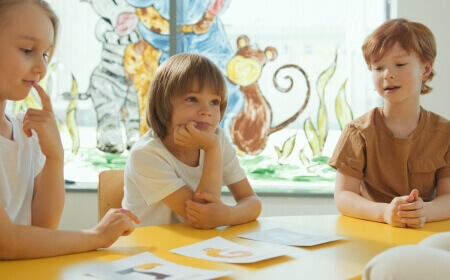 Kita und Schule: Kinder, die am Tisch sitzen und lernen