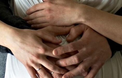 Mann und Frau, die ihre Hände auf den Babybauch legen.